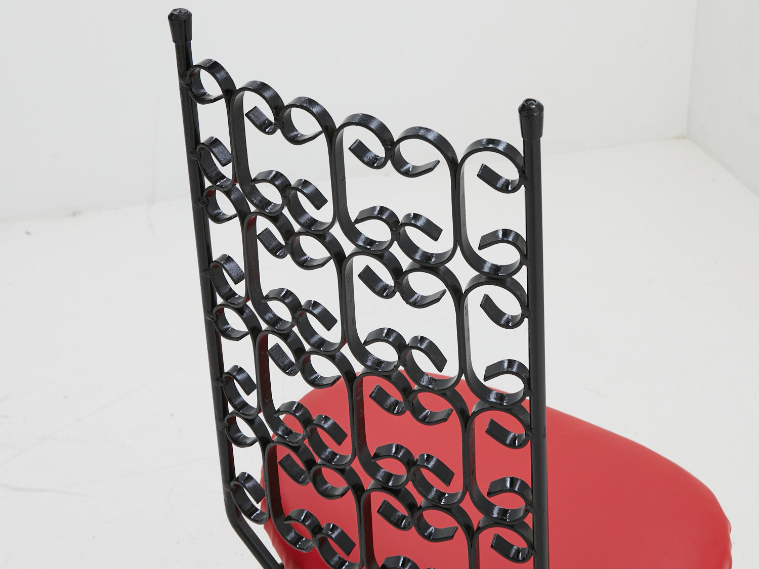 Close up of the back iron scroll dining chair designed by Arthur Umanoff with red seat cushion