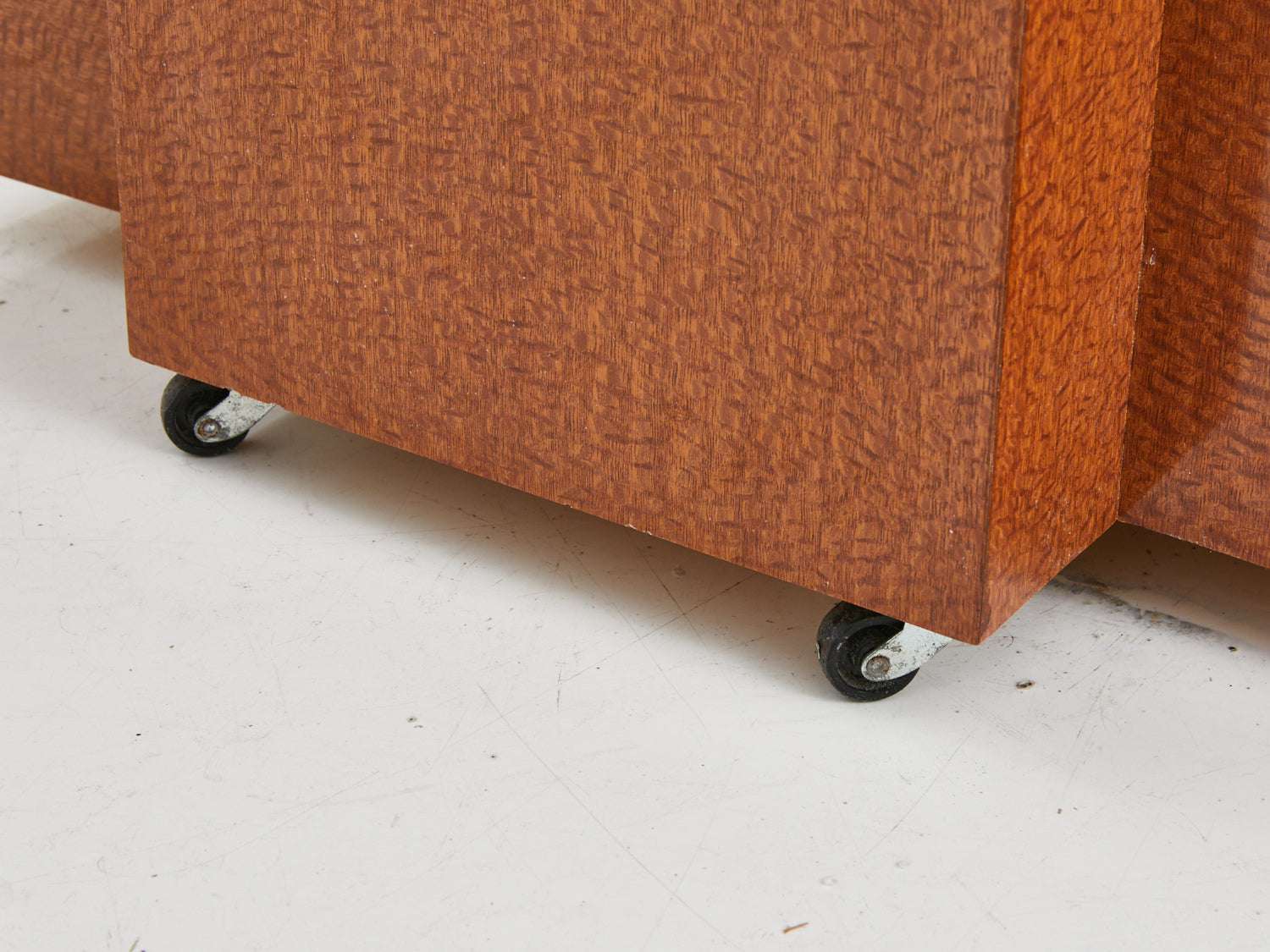 Caster feet on the base of a faux wood geometric pedestal from the 1980s