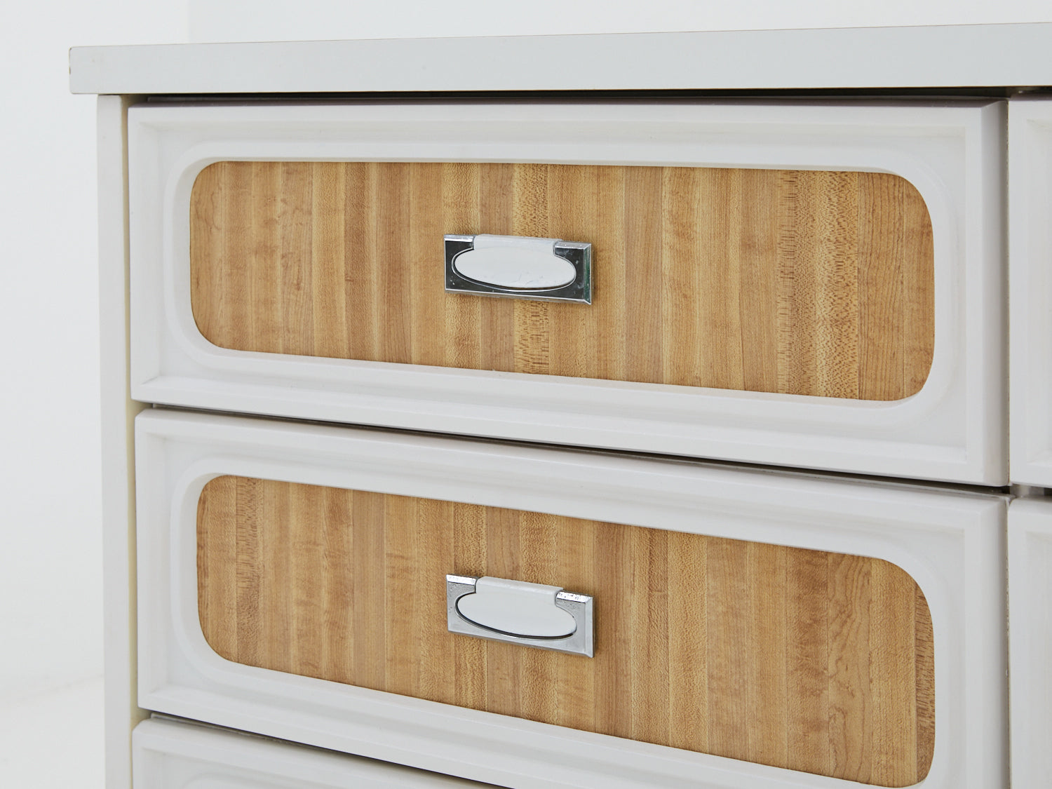 Close up of drawers on a faux wood formica dresser