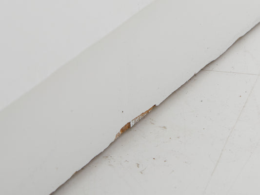 Close up of damage to the base of a white dresser